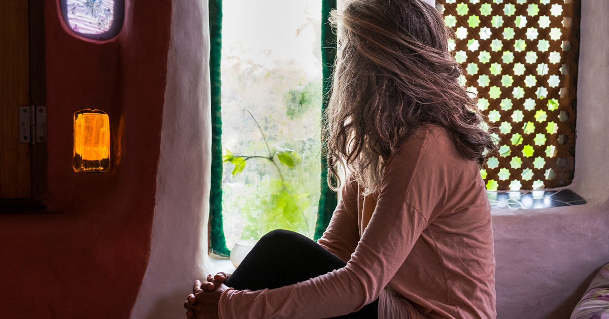 Woman sitting by a window looking contemplative Amberly Neese blog on anxiety and faith